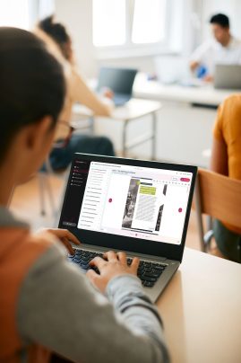 Close-up of high school student using laptop during computer class at school.